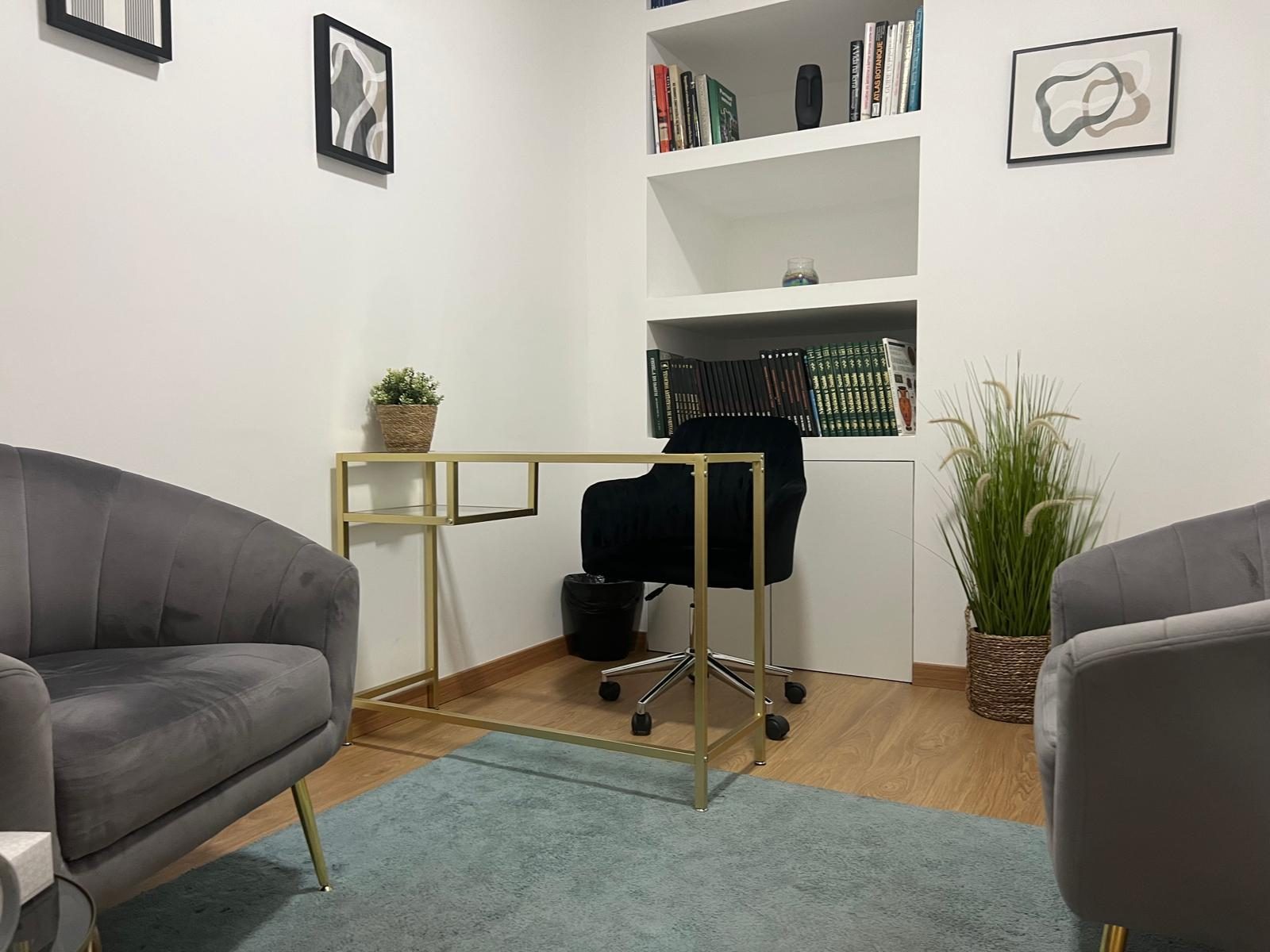 Consultório de psicologia da Clínica dos Afectos em Setúbal, com poltronas cinzentas e secretária dourada